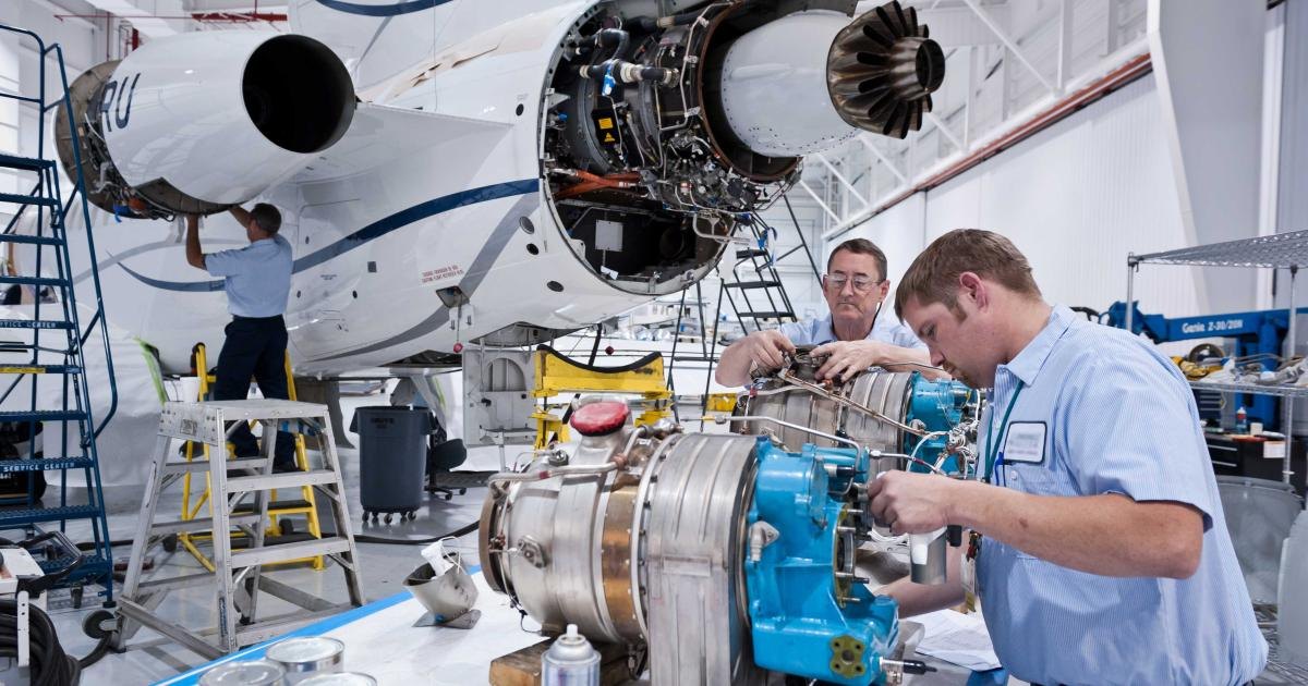 Technicians servicing a business jet engine in a maintenance hangar